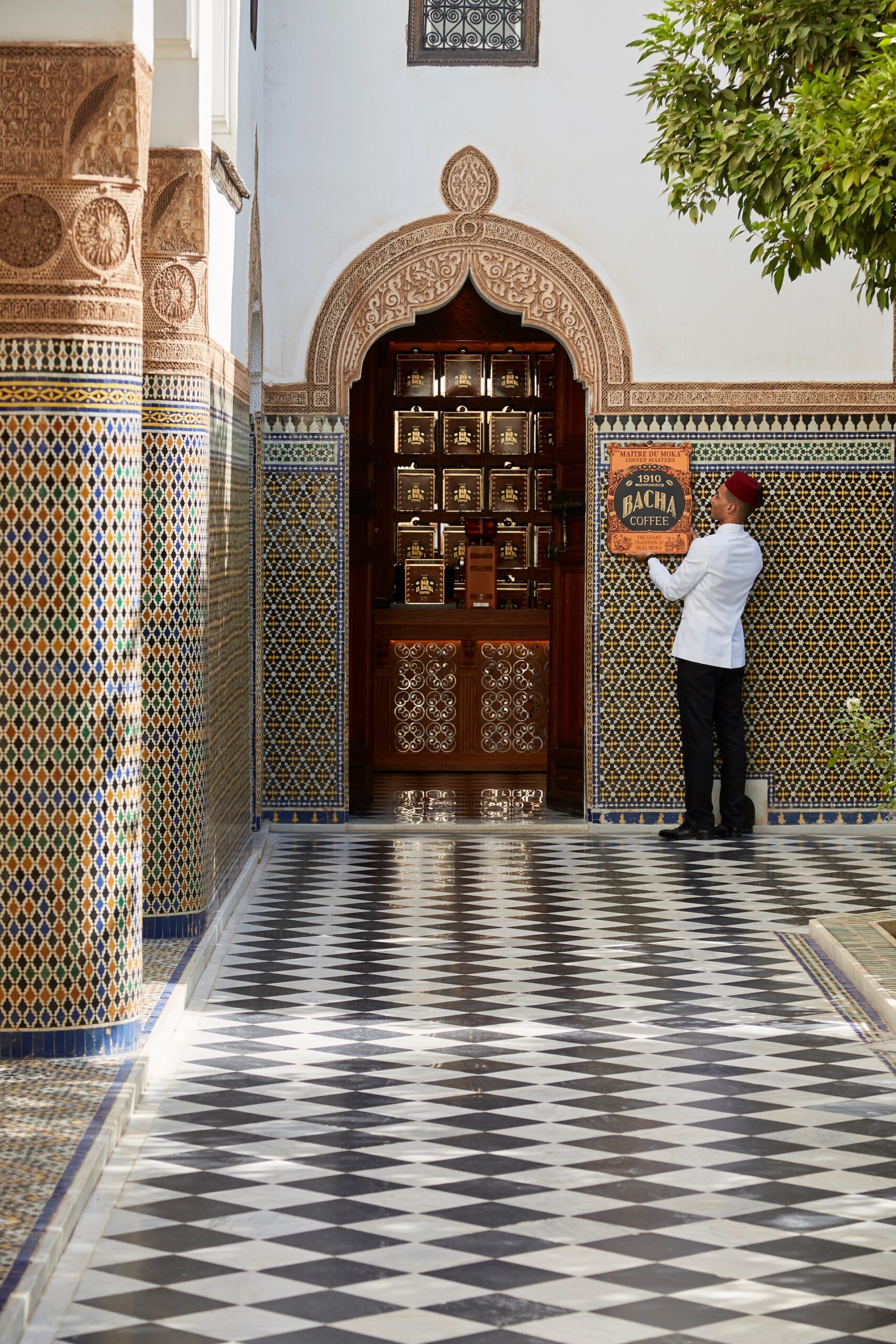 Bacha Coffee Dar el Bacha Marrakech – A Bacha Coffee Master places a Bacha Coffee sign on a wall in the courtyard of Dar El Bacha, Marrakech.